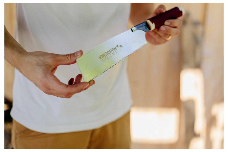 Person holding a kitchen knife with a green blade labeled 'KIRSCHEN'.