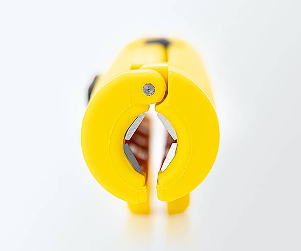 A yellow wire stripper tool with an open circular blade is placed vertically on a white surface, showing its sharp cutting edge.