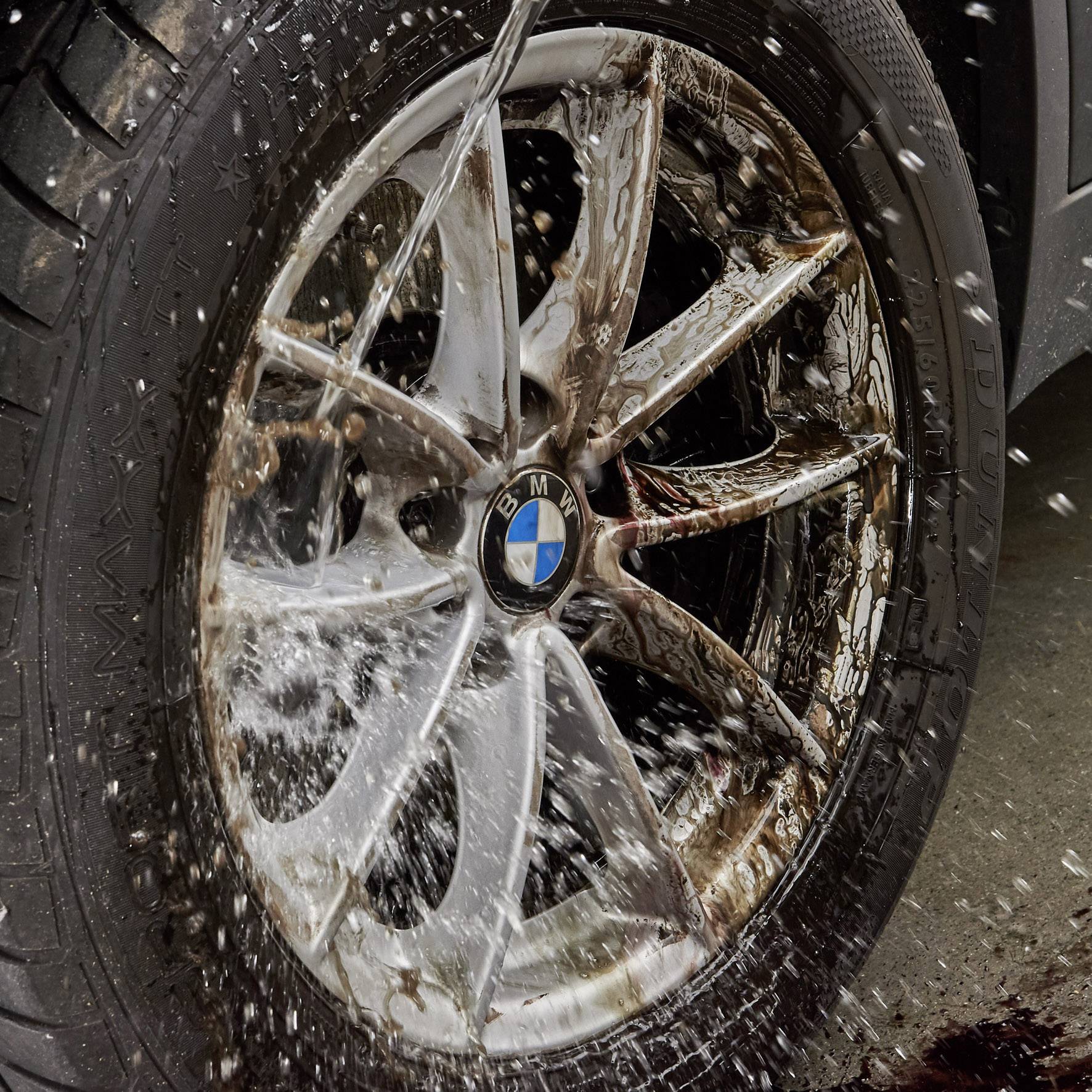 A car tyre is sprayed with water. The alloy wheel belongs to a BMW. The image shows the dynamic movement of the water.