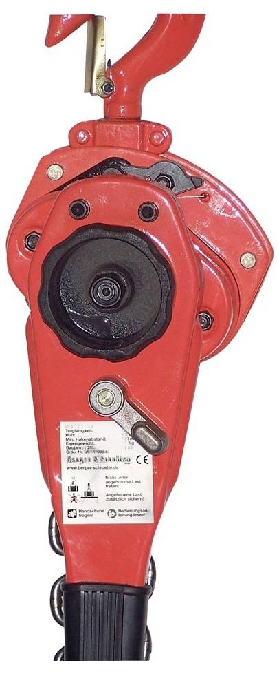 Close-up of a red industrial hand tool or brake-like mechanism with a large black central wheel and a small label on the handle.