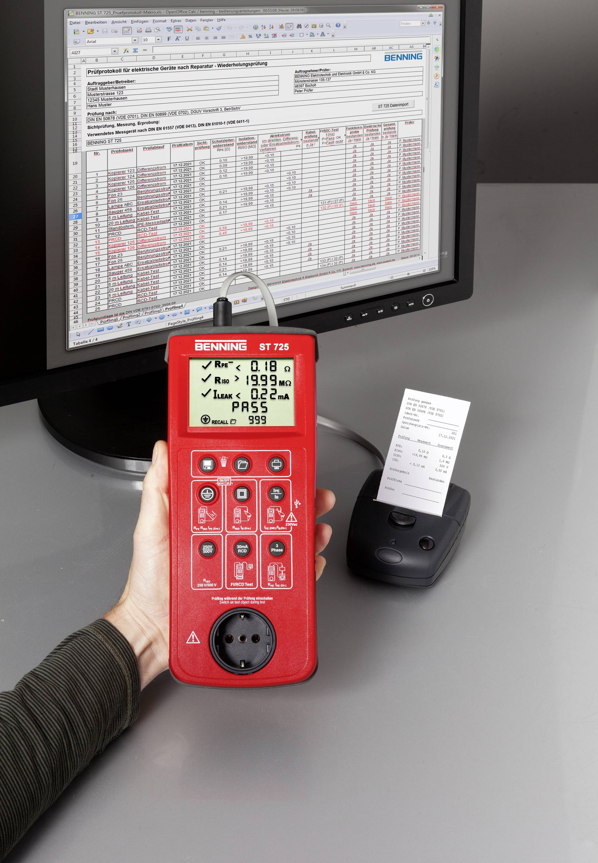 A person is holding a measuring device in front of a screen displaying a table. A small printer with a printout sits next to it on the table.