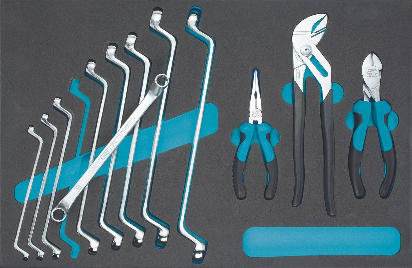 A selection of hand tools, including curved ring spanners, side cutters, long-nose pliers and water pump pliers on a grey background.