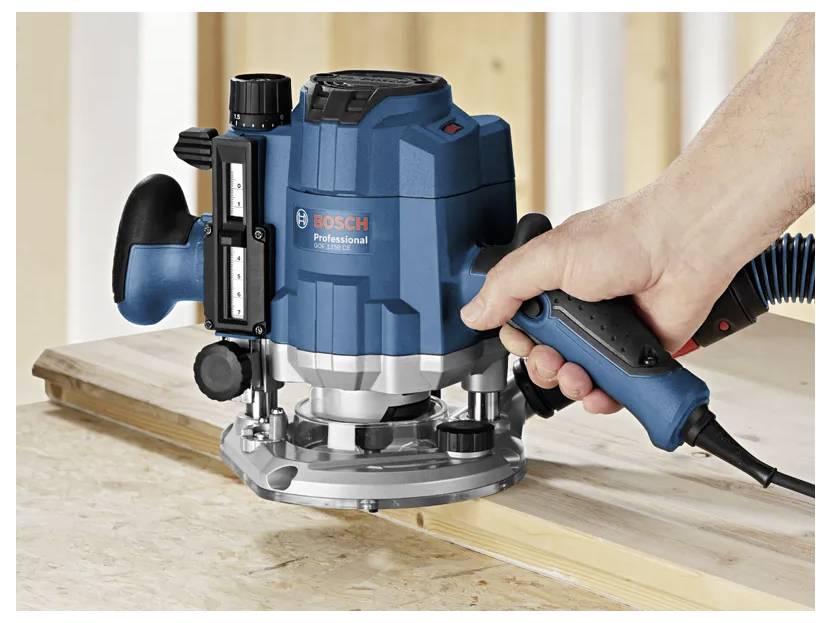 Hand using a Bosch Professional plunge router to cut a groove in a wooden board.