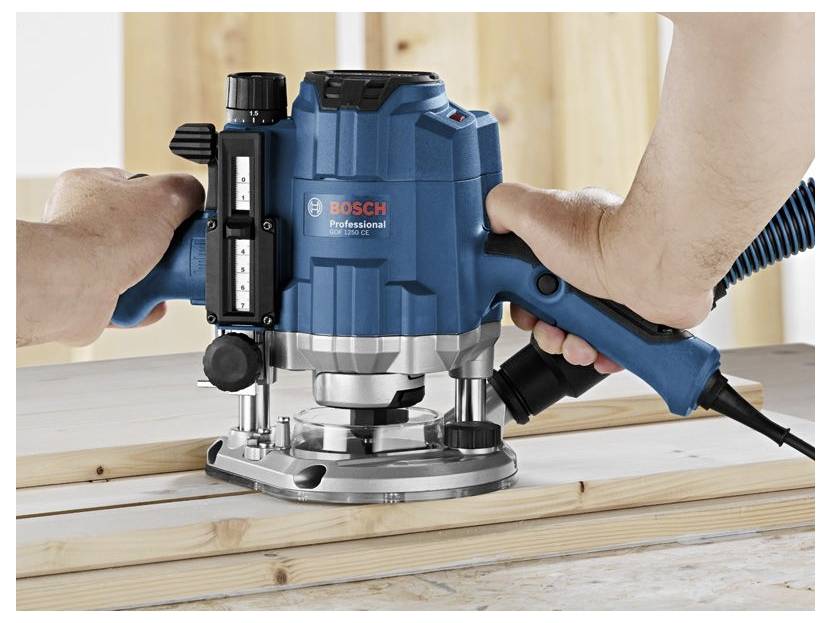 Hands using a Bosch Professional router to shape a wooden board on a workbench.
