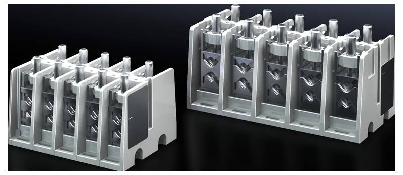 Two grey, block-shaped metal components with multiple vertical elements lying side by side on a dark surface.