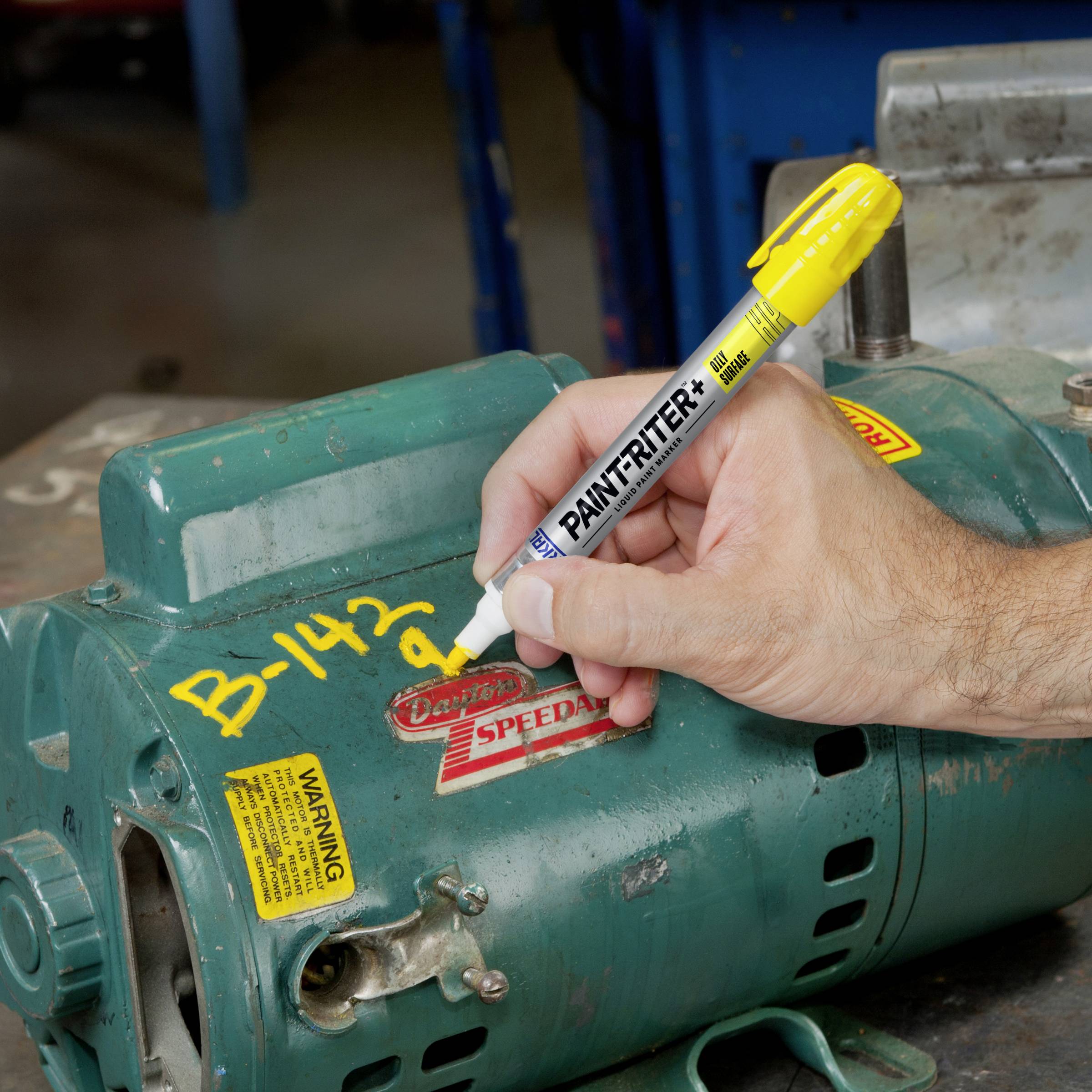 A yellow highlighter writes the number 'B-143' on a green metal surface that appears to be part of a machine.