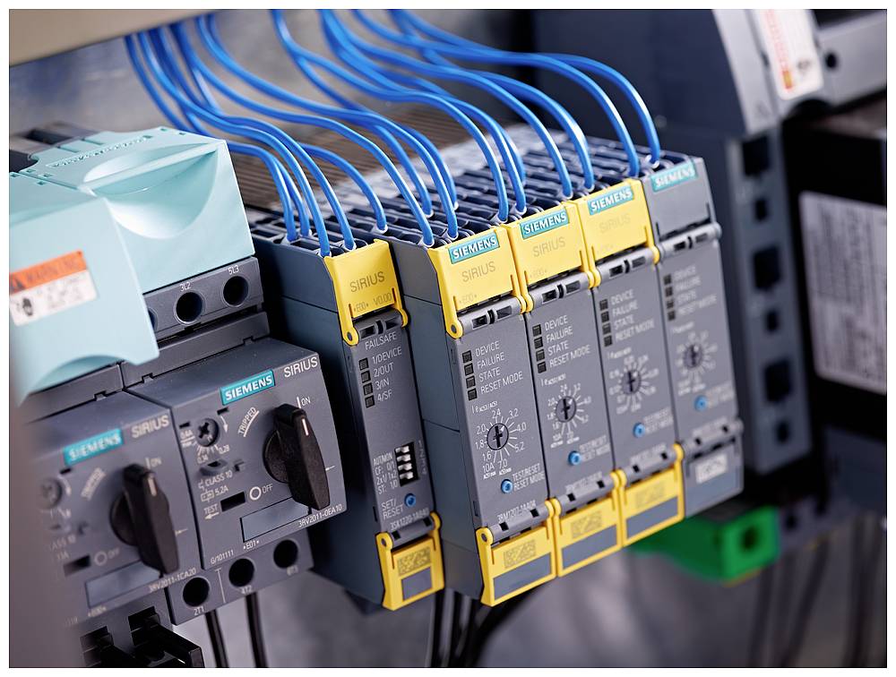 Close-up of an electrical control panel with multiple blue cables connected to grey and yellow Siemens components.