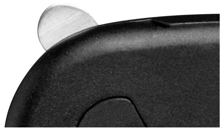 A close-up shows the corner of a dark grey housing with a silver button or lever at the edge.