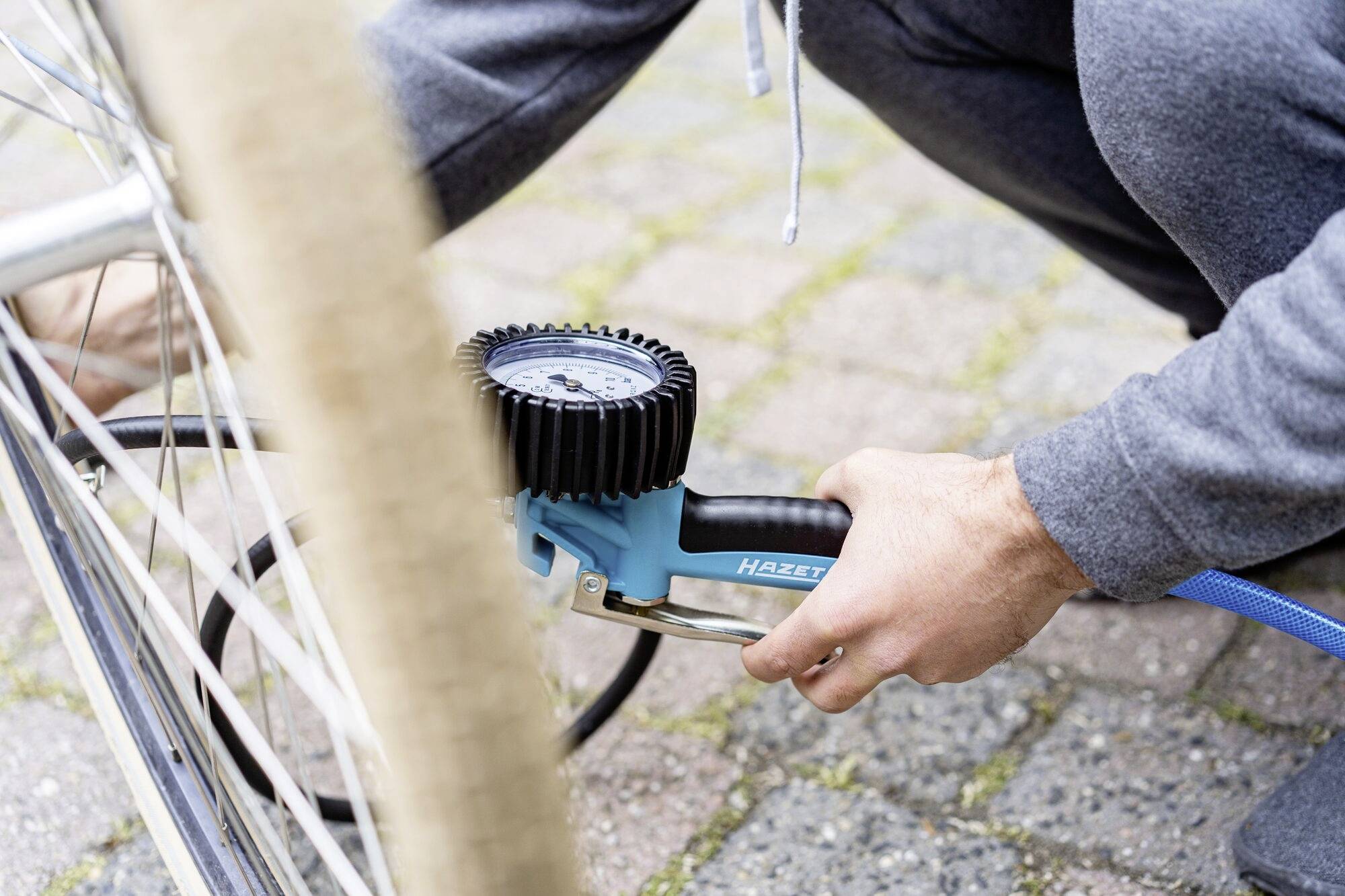 A person is inflating a bicycle tyre with a bicycle pump. The focus is on pumping up the tyre.