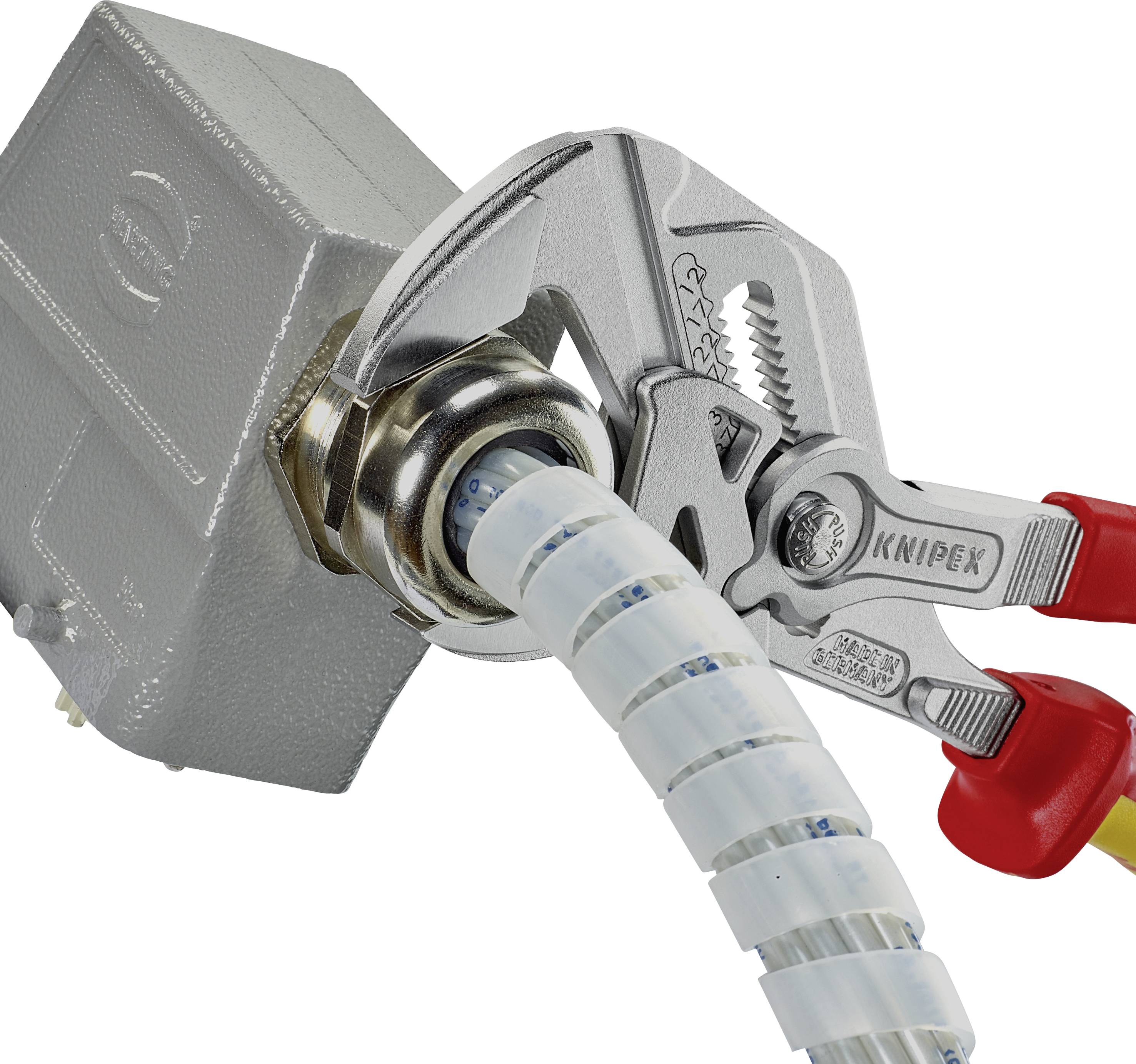 A pair of pliers grips a metal nut on a cable emerging from a socket. The pliers have red handles.
