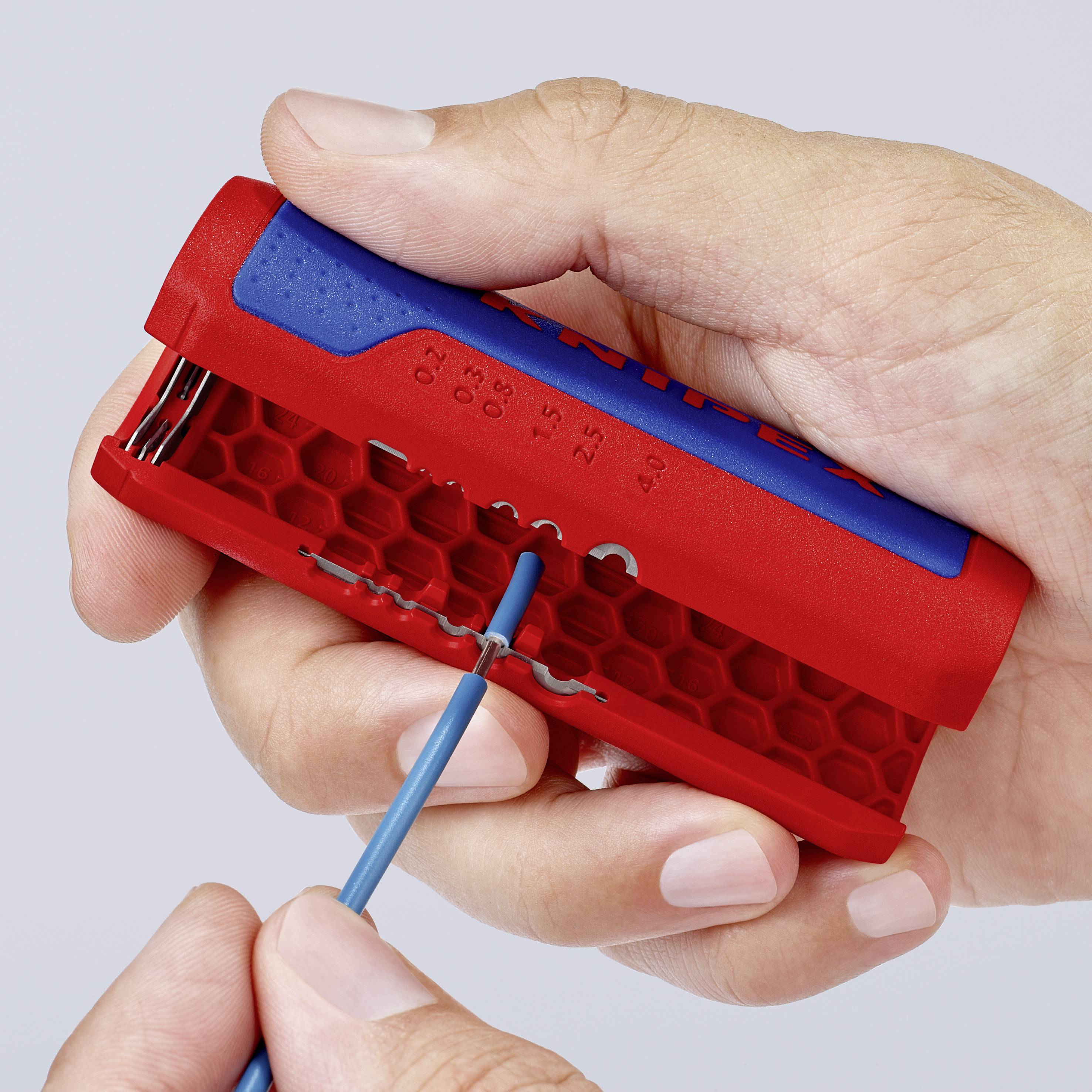 A person is holding a red, honeycomb-shaped tool and removing a blue cable insulation with a wire stripper.