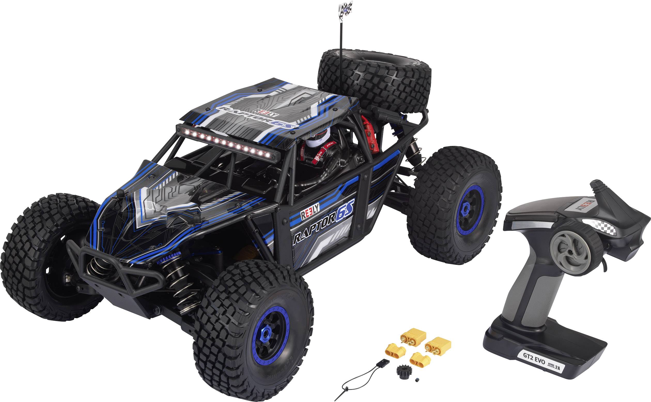 A remote-controlled car with robust tyres and a spare wheel on the back. Beside it lies a grey remote control.
