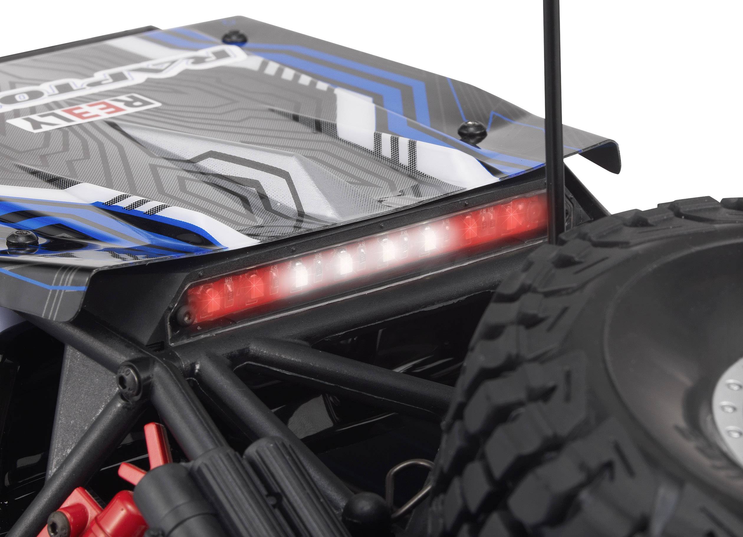 Close-up of a remote-controlled car with chunky profile tyres and a glowing red LED strip on the rear.