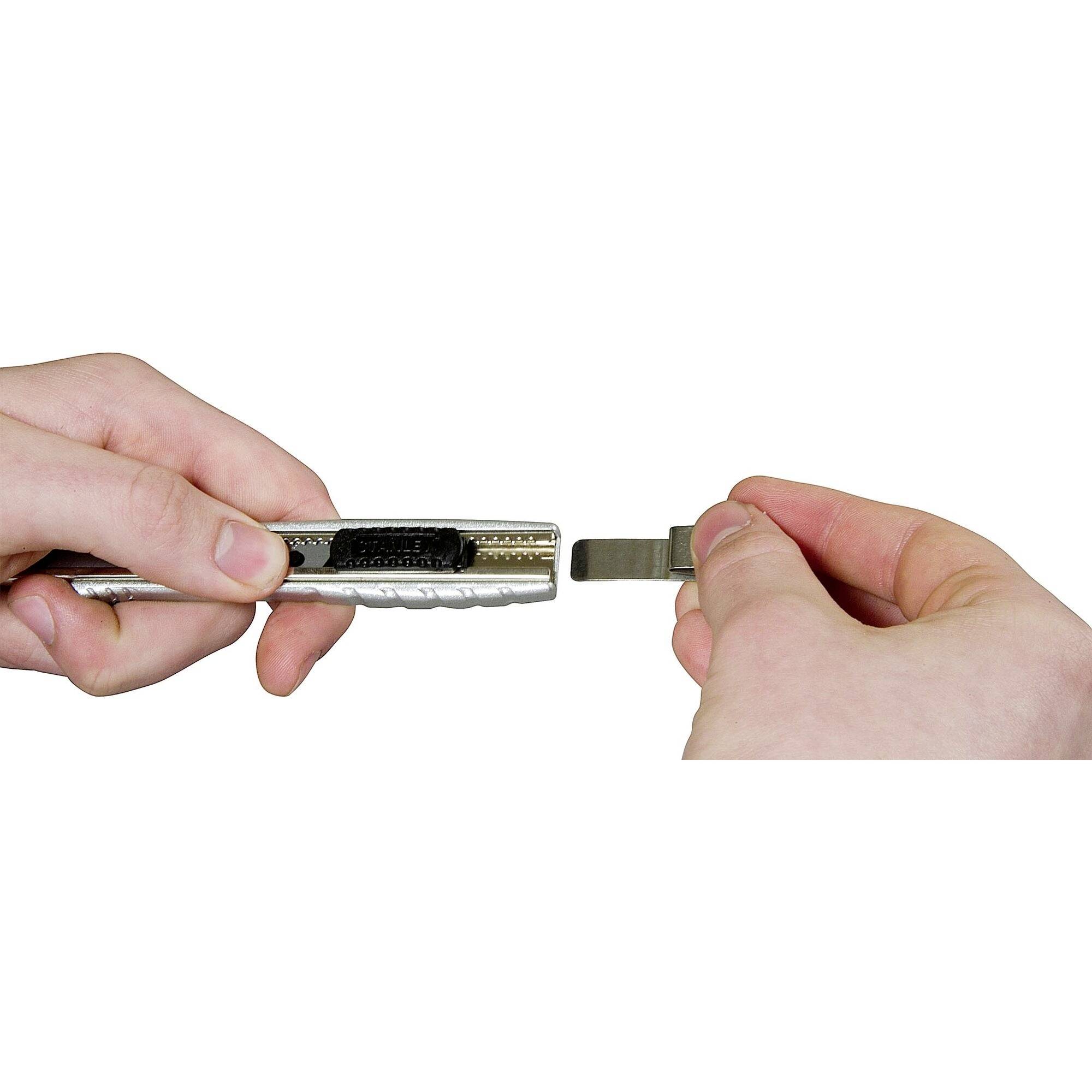 Two hands are holding a cutting tool and a removable blade, presumably the blade is being changed or removed.