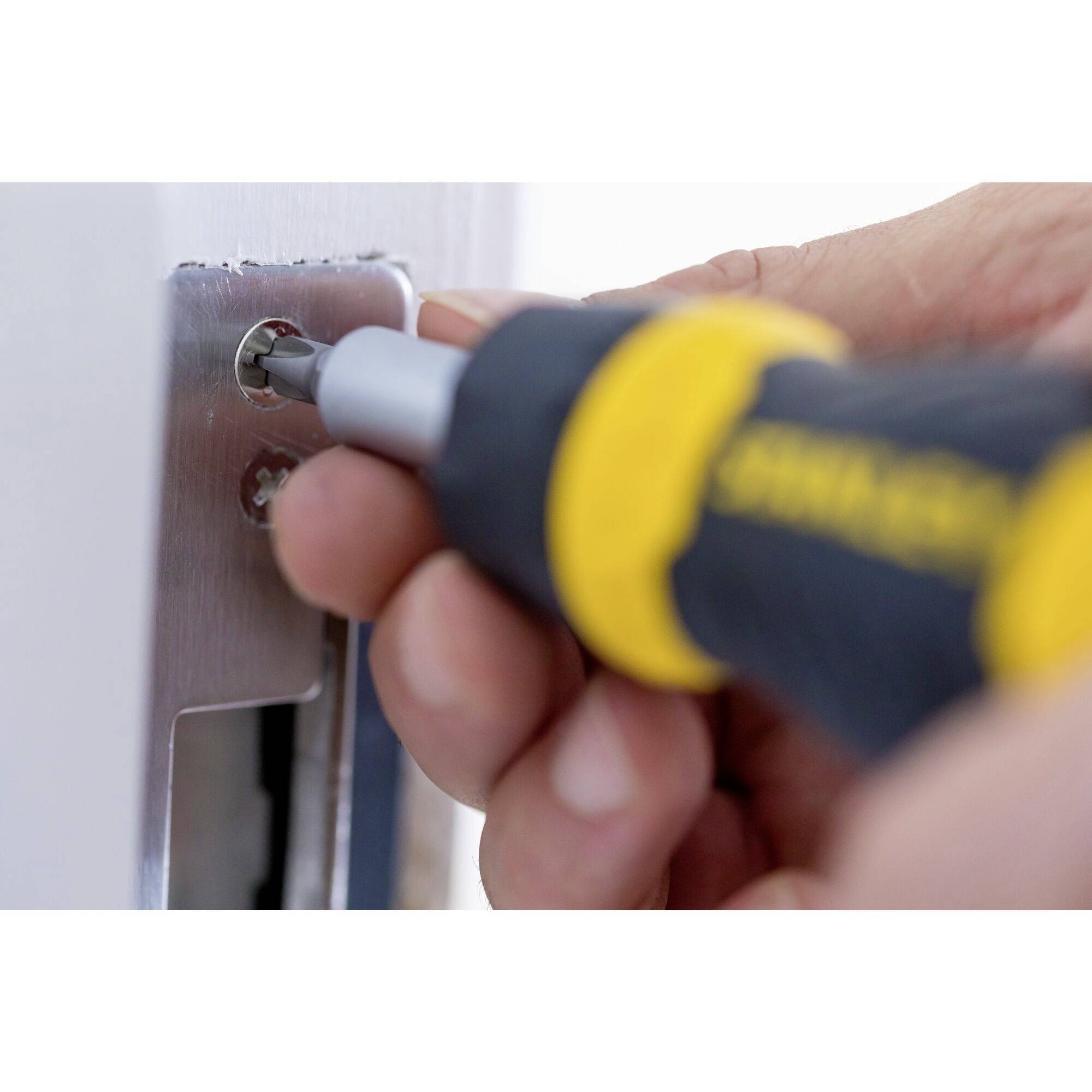 A person is repairing a door with a screwdriver being inserted into a lock.