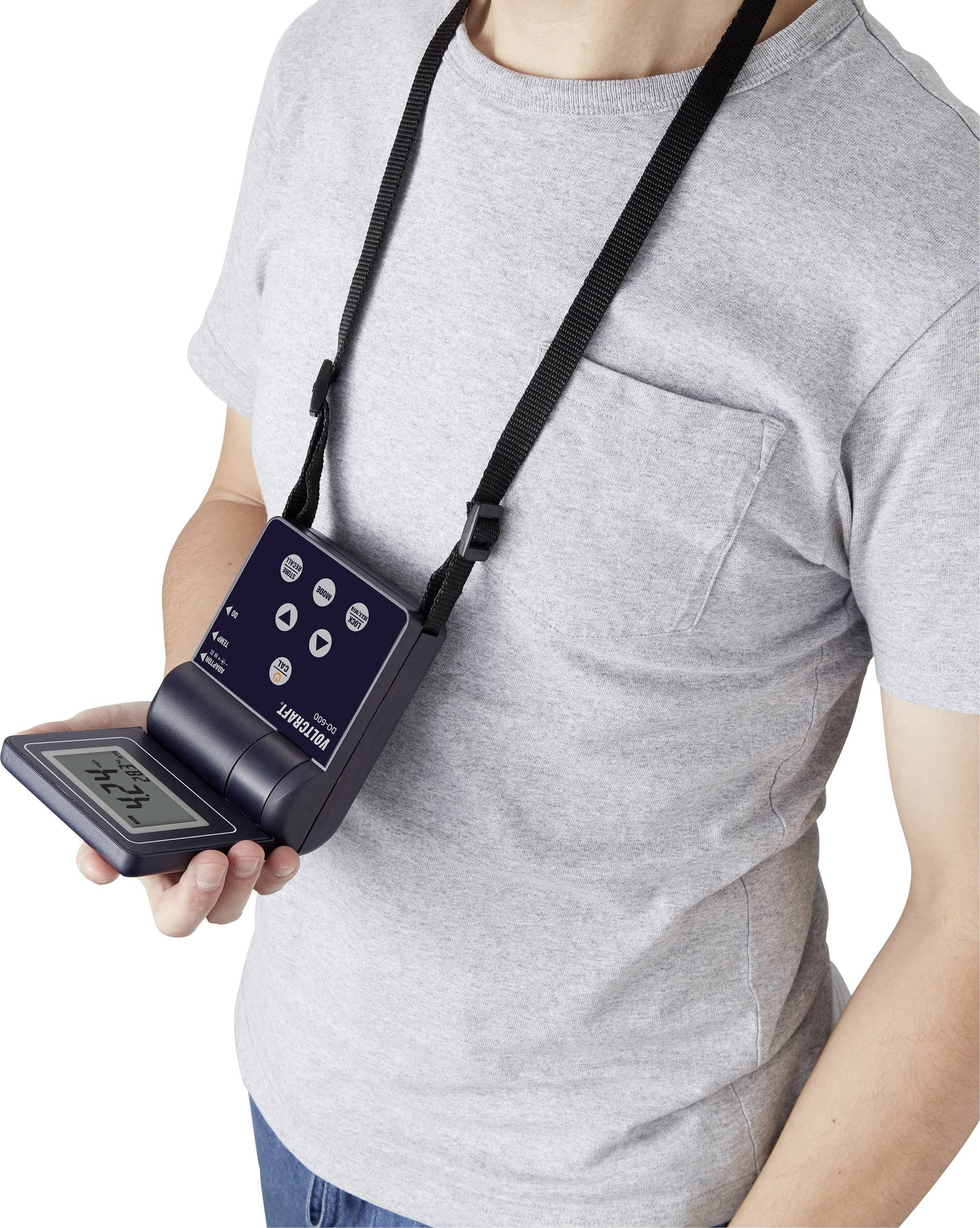 A person is wearing a portable electronic device on a lanyard around their neck. The device displays a digital screen with numbers.