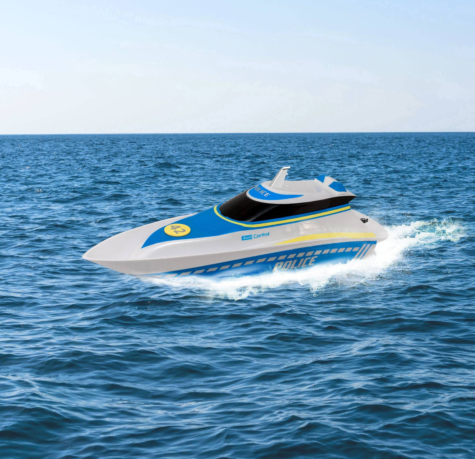 A blue and white police boat speeds across the sea, which is uniformly blue and calm.
