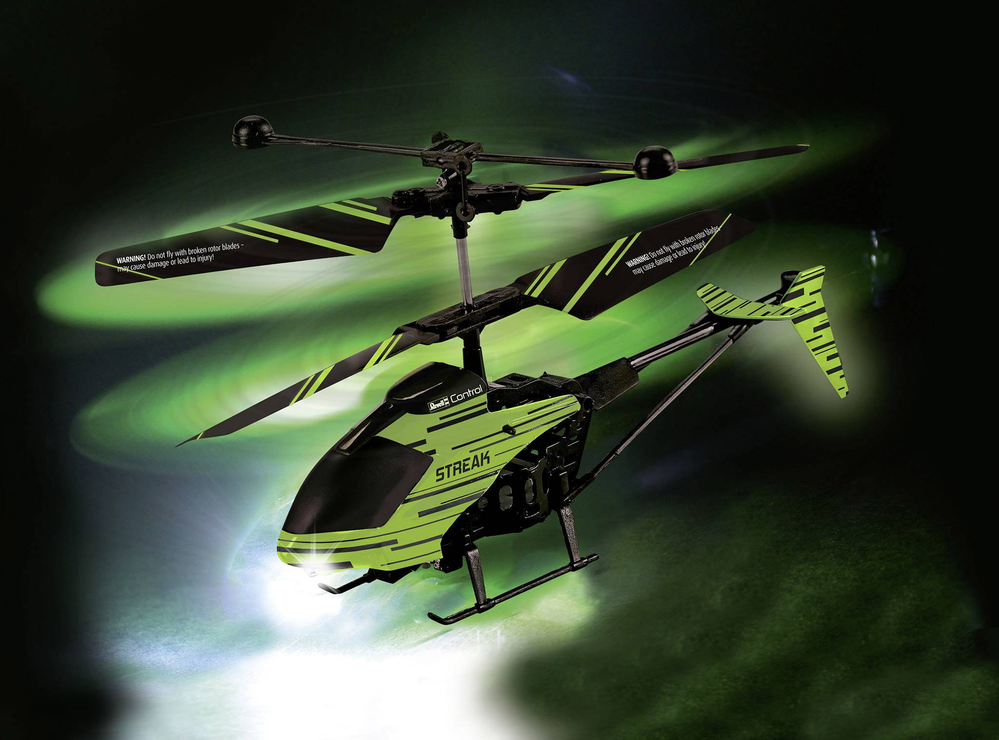 A remote-controlled helicopter in black and green with two rotors, flying against a dark background.