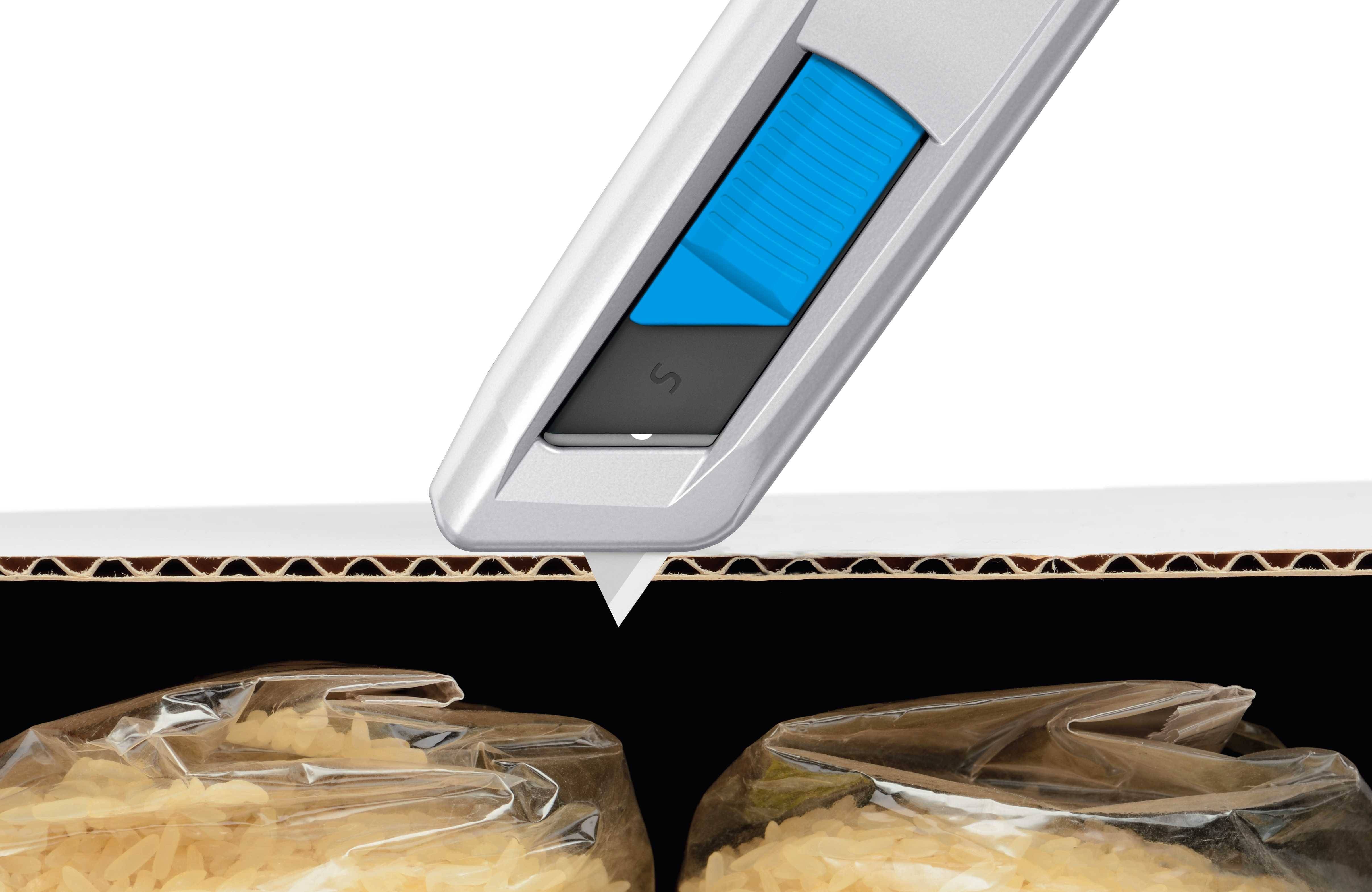 A silver carpet knife with a blue handle cuts clean lines between two vacuum-packed bags of rice grains.