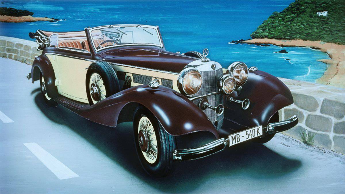 A classic convertible drives along a coastal road, with the sea and a forested peninsula visible in the background.