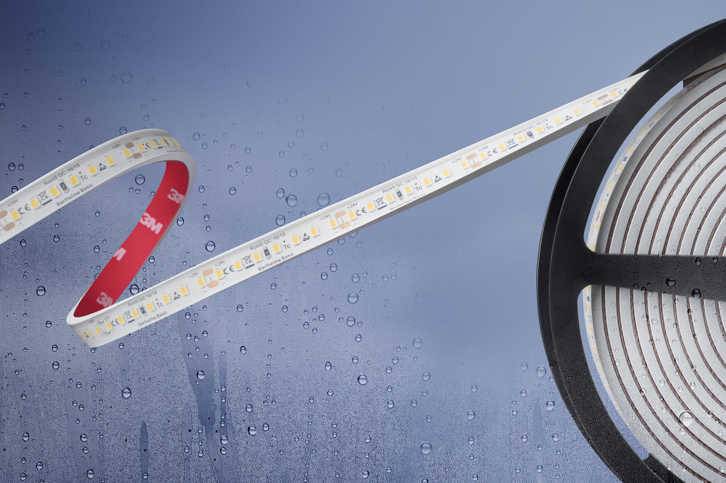 A roll of flexible LED strips with illuminated diodes, partially unrolled, against a background with water droplets.