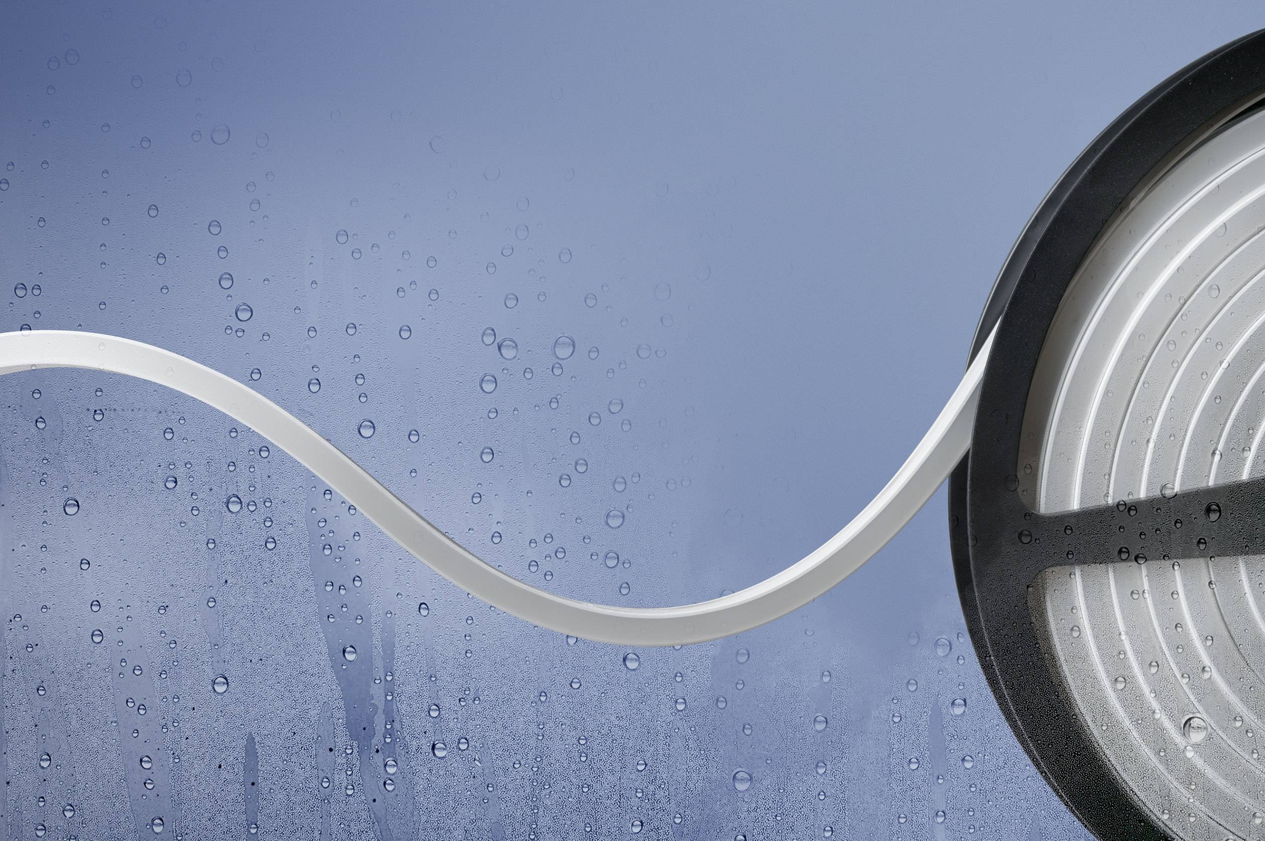 A white, ribbon-like LED strip on a reel, with a background of water droplets on a glass surface, conveys a modern design.