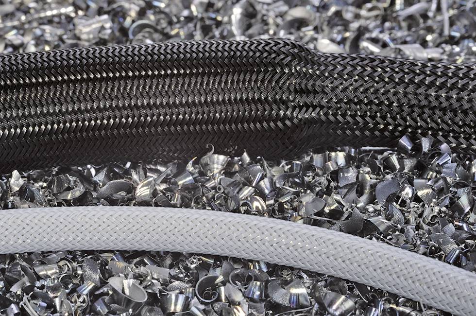 Two hoses, one black and one grey, are lying on a pile of metal shavings.