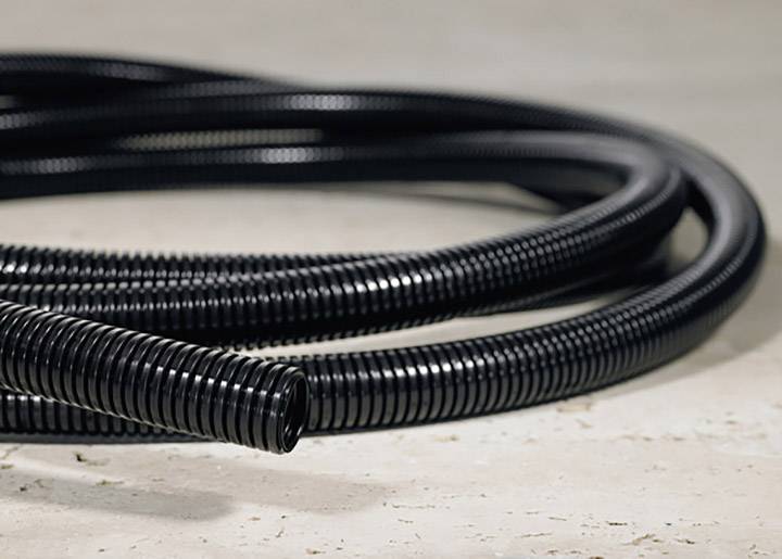 Black, ribbed plastic hosepipe on a concrete floor. The hosepipe is long and laid out in several coils.