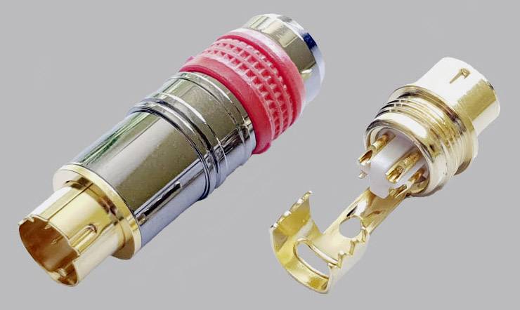 An XLR plug and its internal components, with gold-plated contacts and a red plastic ring, for audio connection.
