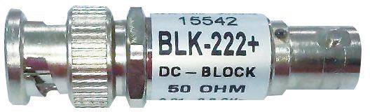 A silver coaxial plug marked 'BLK-222+, DC Block, 50 OHM'. It features a knurled metal section for improved grip.
