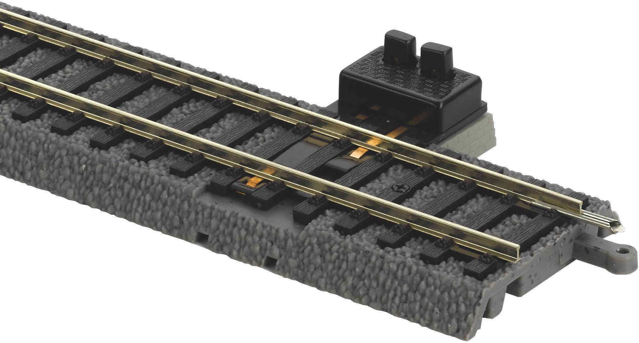 Railway track switch on a grey rail track with an integrated contact mechanism for controlling electric model trains.