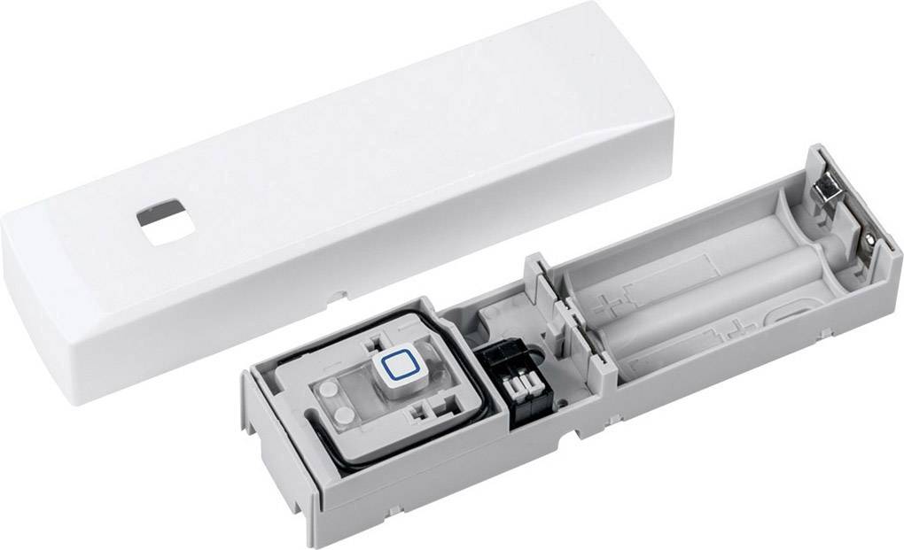 An opened, rectangular device with a battery compartment and electronic components; white lid beside it.