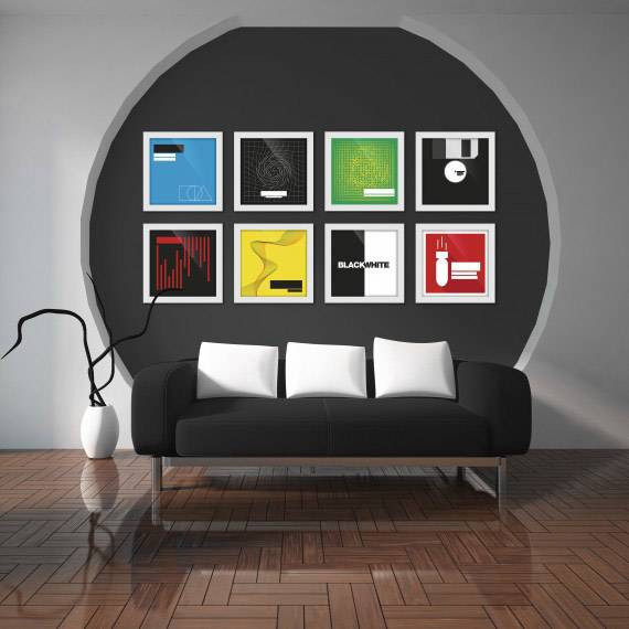 A black sofa with white cushions sits in front of a grey wall decorated with nine colourful, framed pictures.