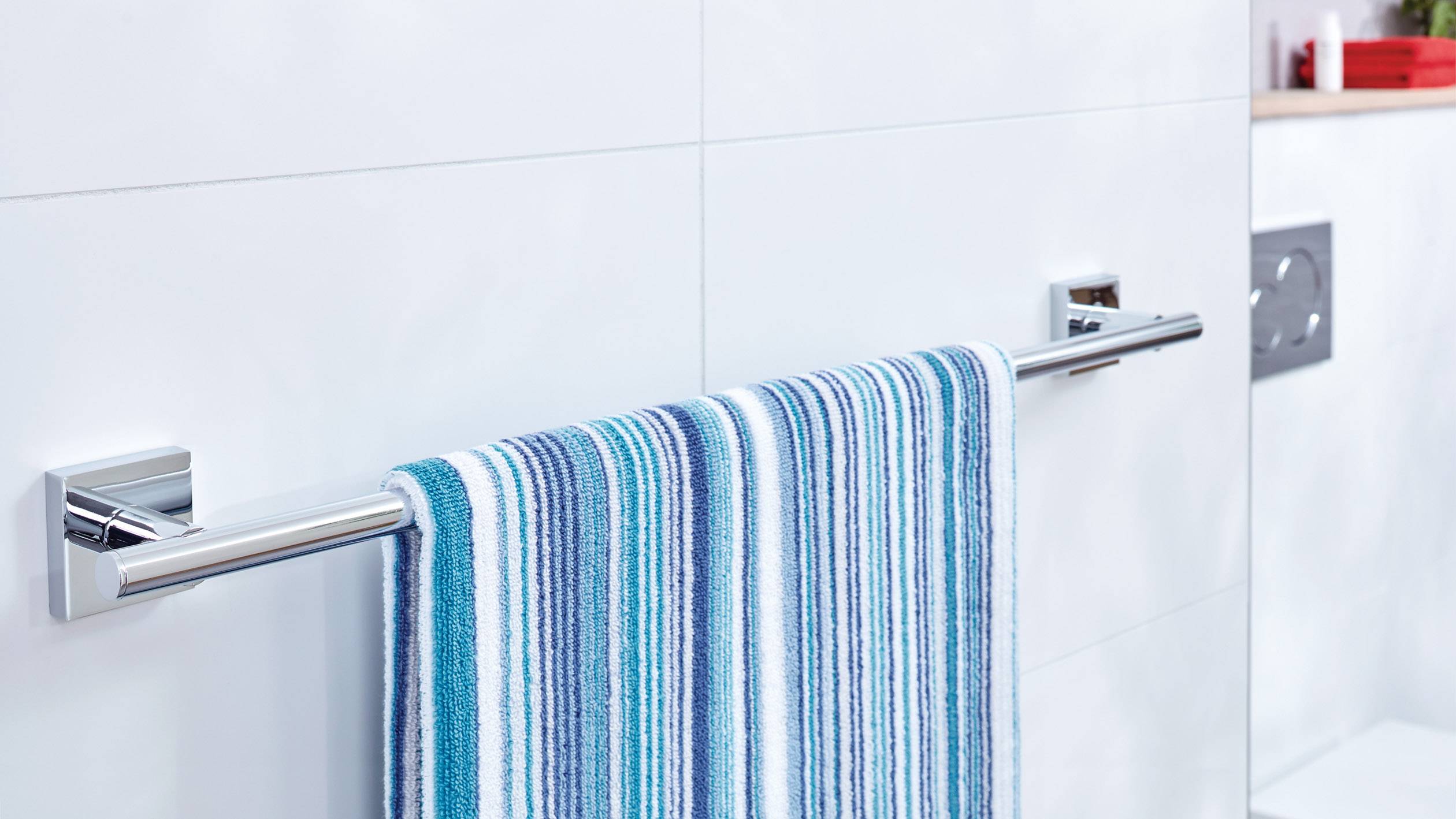 Towel rail with a striped blue towel, mounted on a bathroom wall with white tiles.