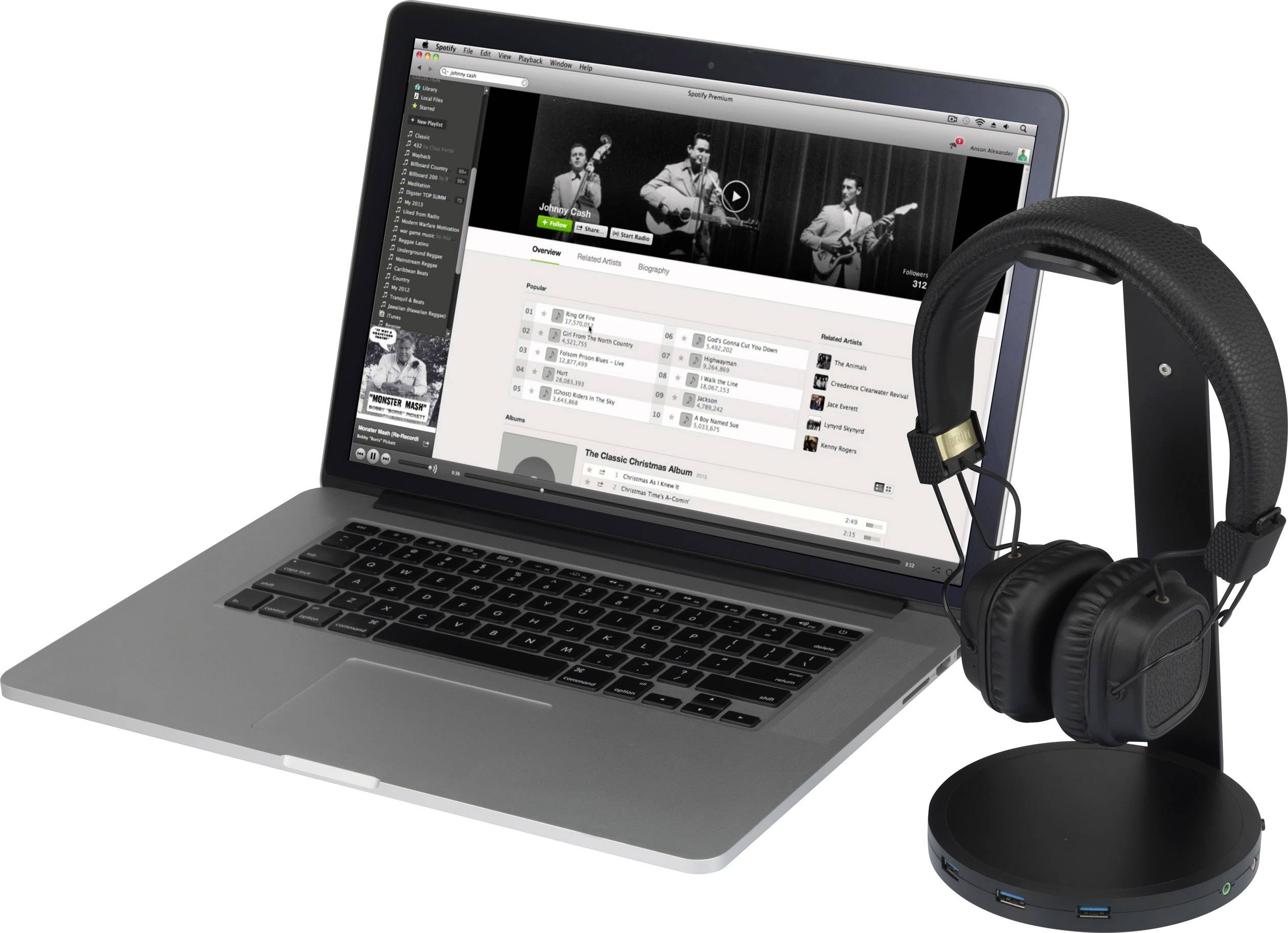 A laptop with an open music streaming service displaying a playlist. Beside it, a black pair of headphones on a stand.