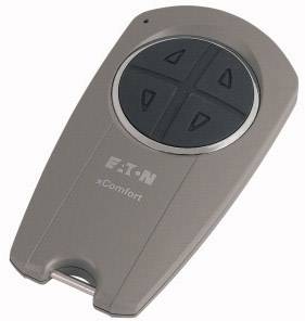 A remote control with four buttons arranged in a circular configuration. The device is grey and bears the inscription 'Eaton xComfort'.