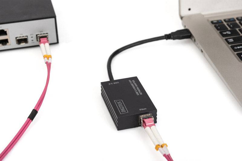 A converter connects a laptop to a network device. A fibre optic cable leads to the laptop, while an Ethernet cable connects the network device.