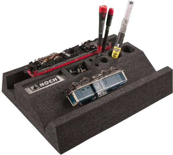 Polystyrene tray with compartments for storing model accessories. Two model trains, a brush, and tools are placed inside.