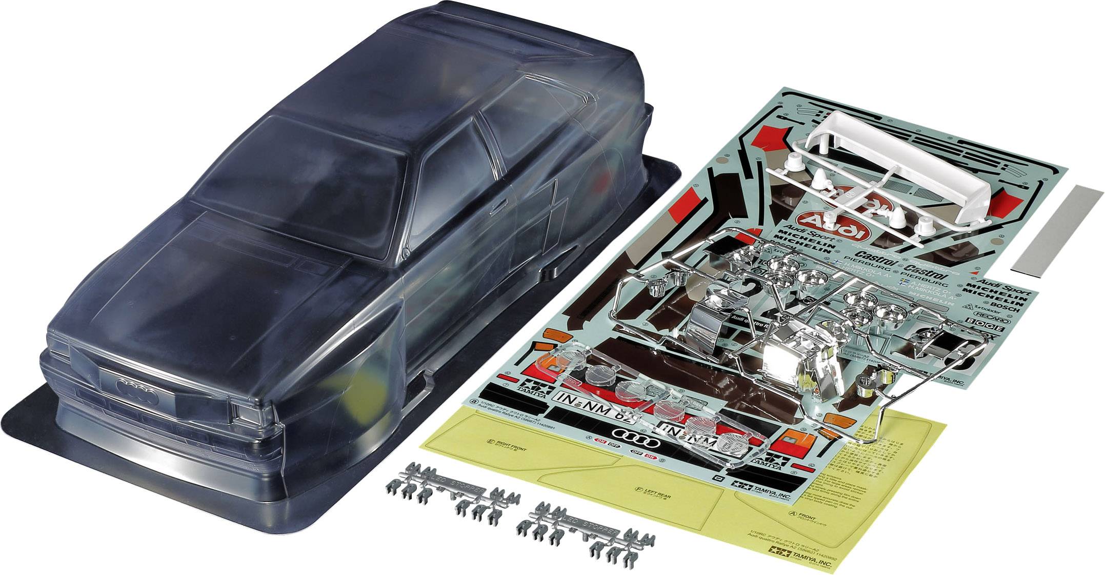 A transparent model car kit with bodywork, decals, and small parts for assembly lies on a table.