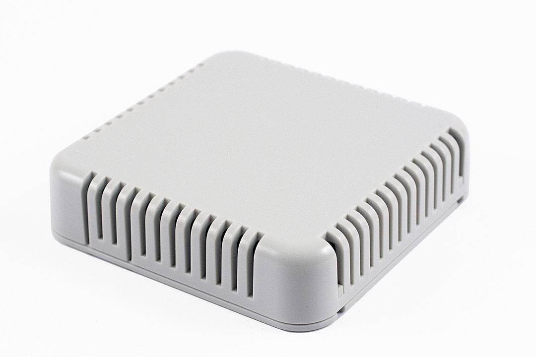 A small, square, white device with ventilation slots on the sides, possibly an electronic enclosure or sensor.