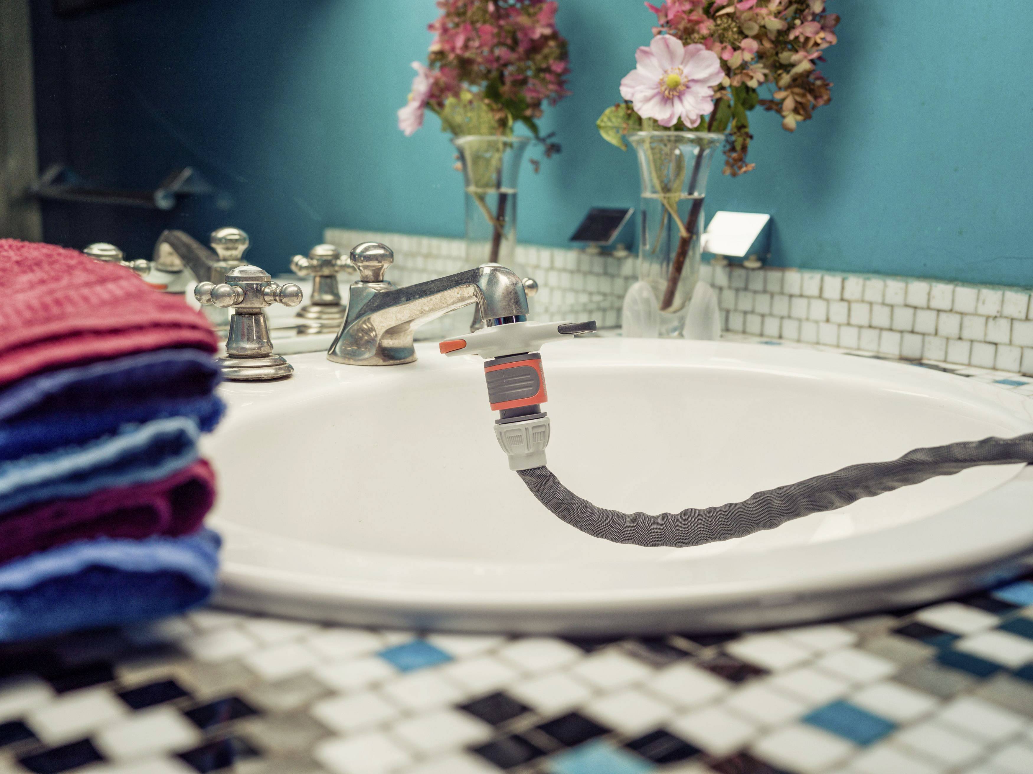 A sink with a running water stream and a tap, decorated with flowers and towels.