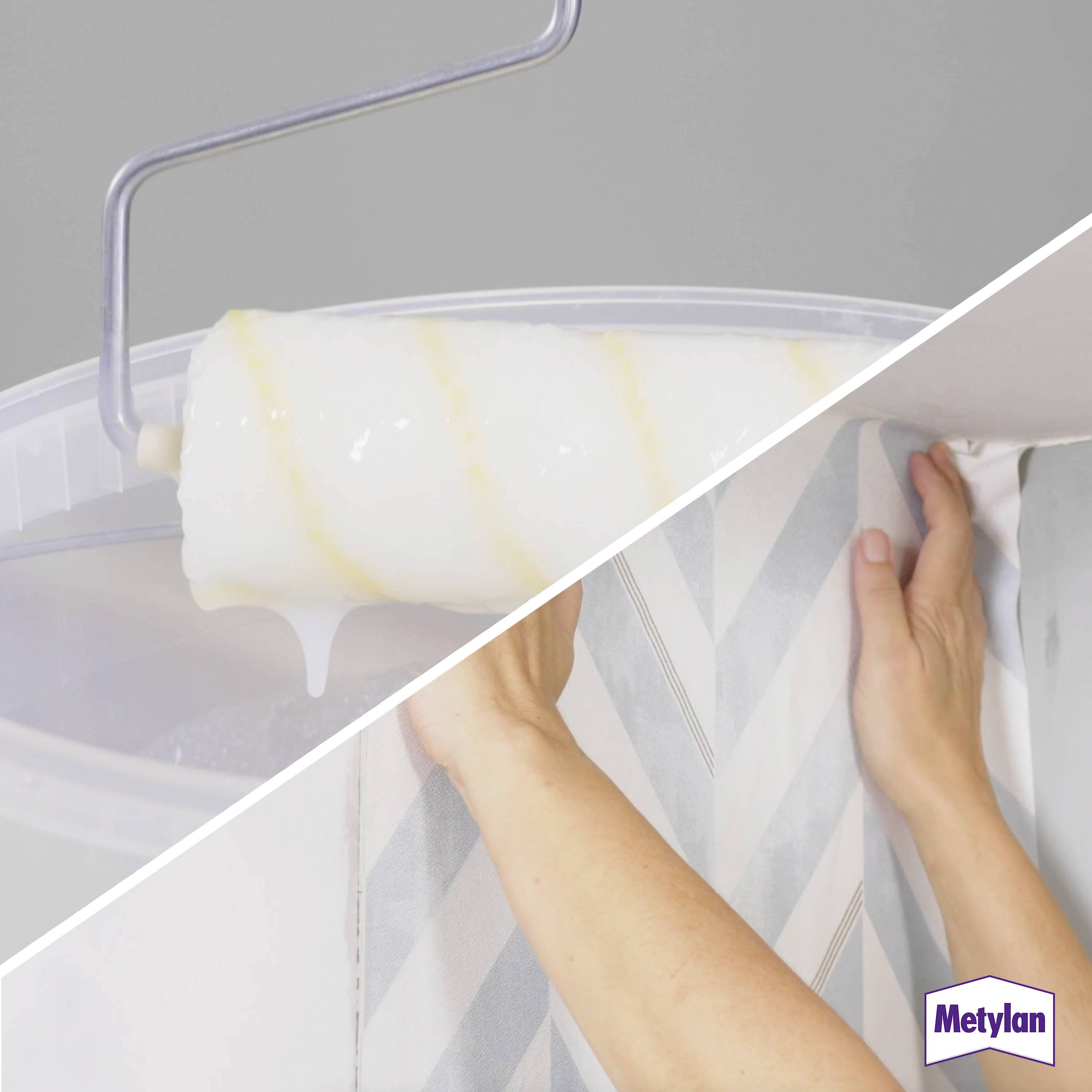 A hand applies a wallpaper strip with a geometric pattern to a wall. A roller with glue is shown in use.