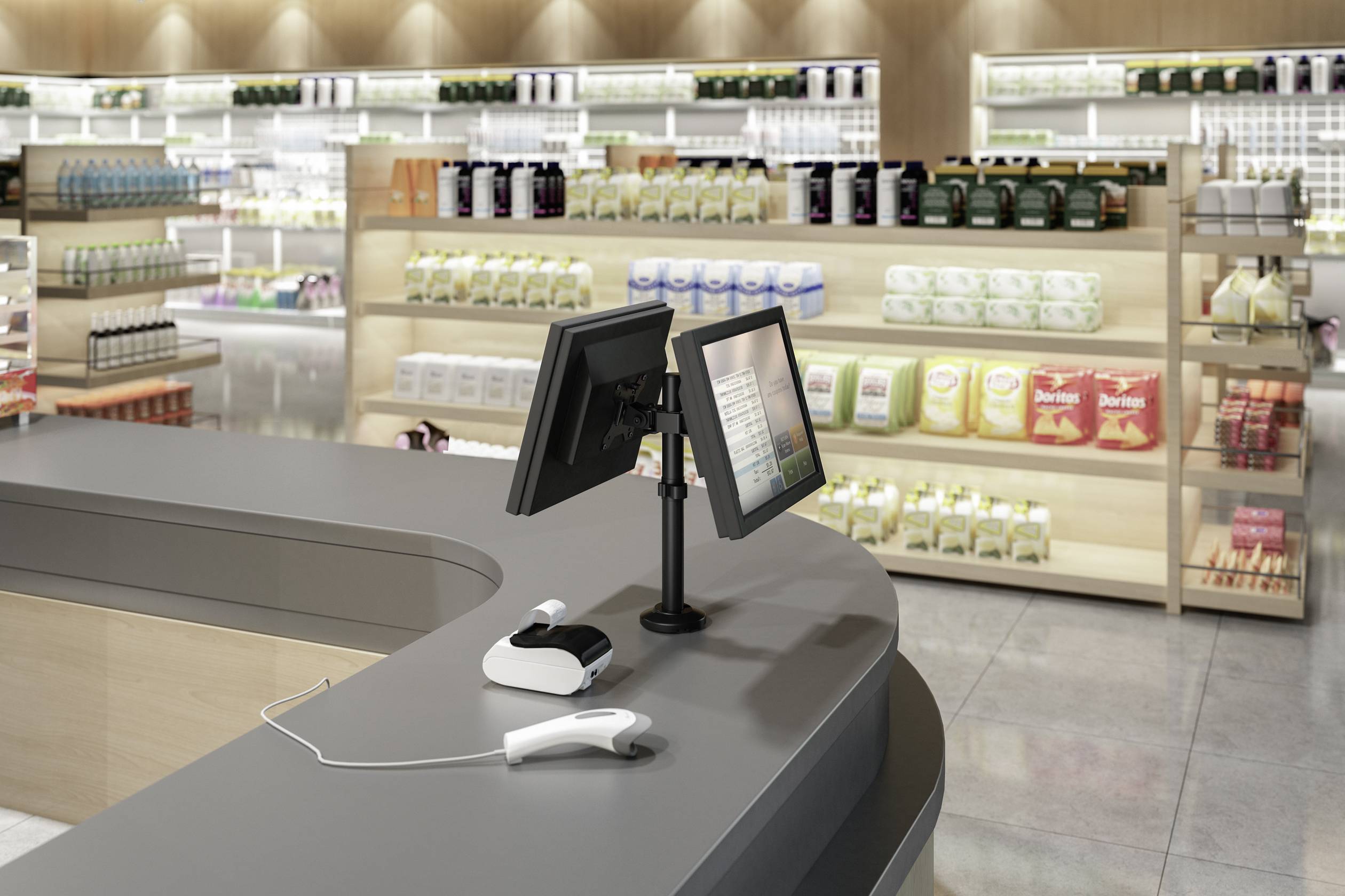 Checkout till in a supermarket with two screens and a scanner on the counter, with shelves of food and products in the background.