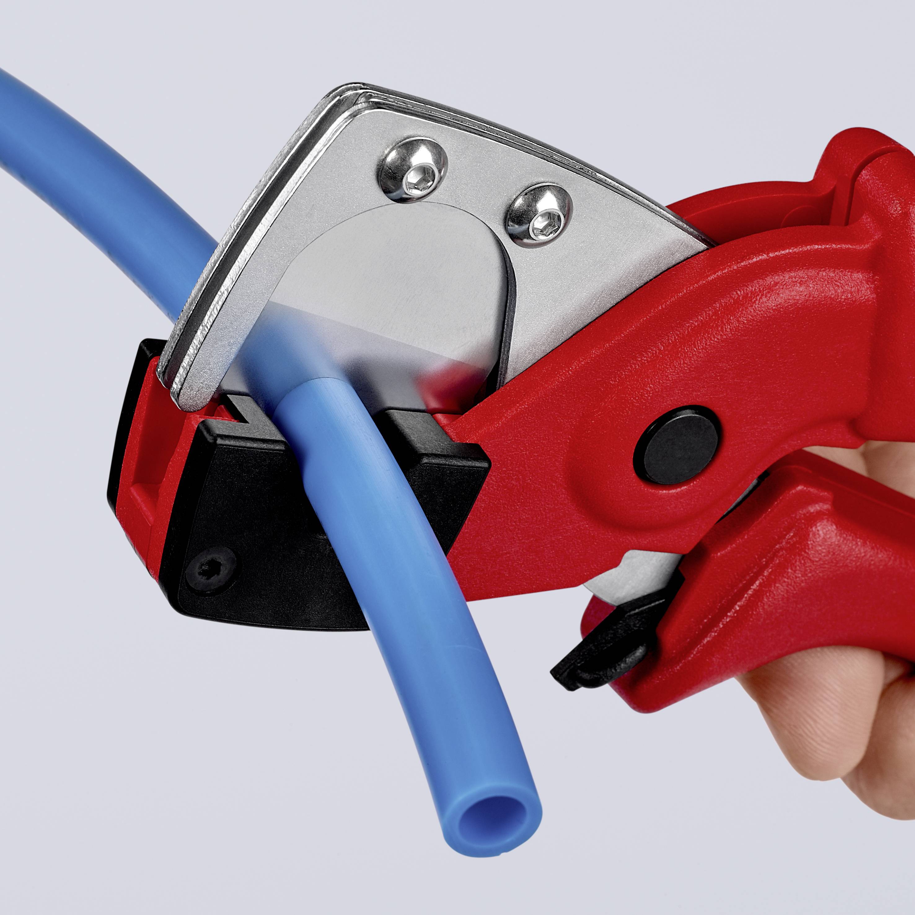 A hand is cutting a blue pipe with a red pipe cutter, close-up view.
