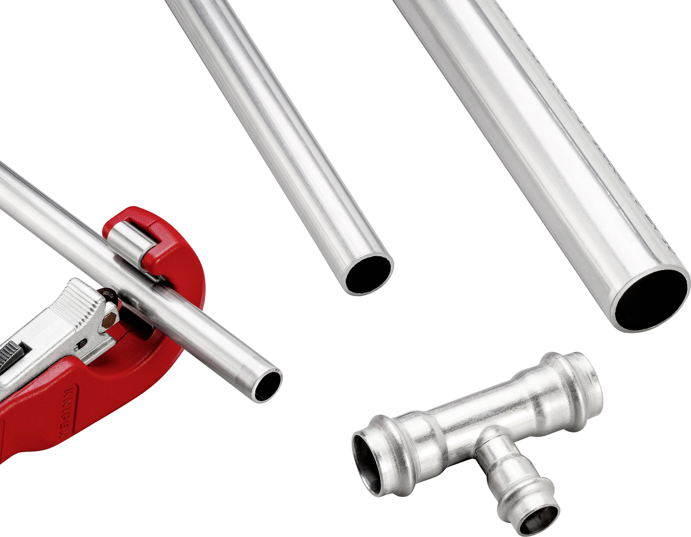 Metal pipes and a T-piece lie side by side. A pipe cutter is cutting one of the pipes. Tools and materials for installing pipework.