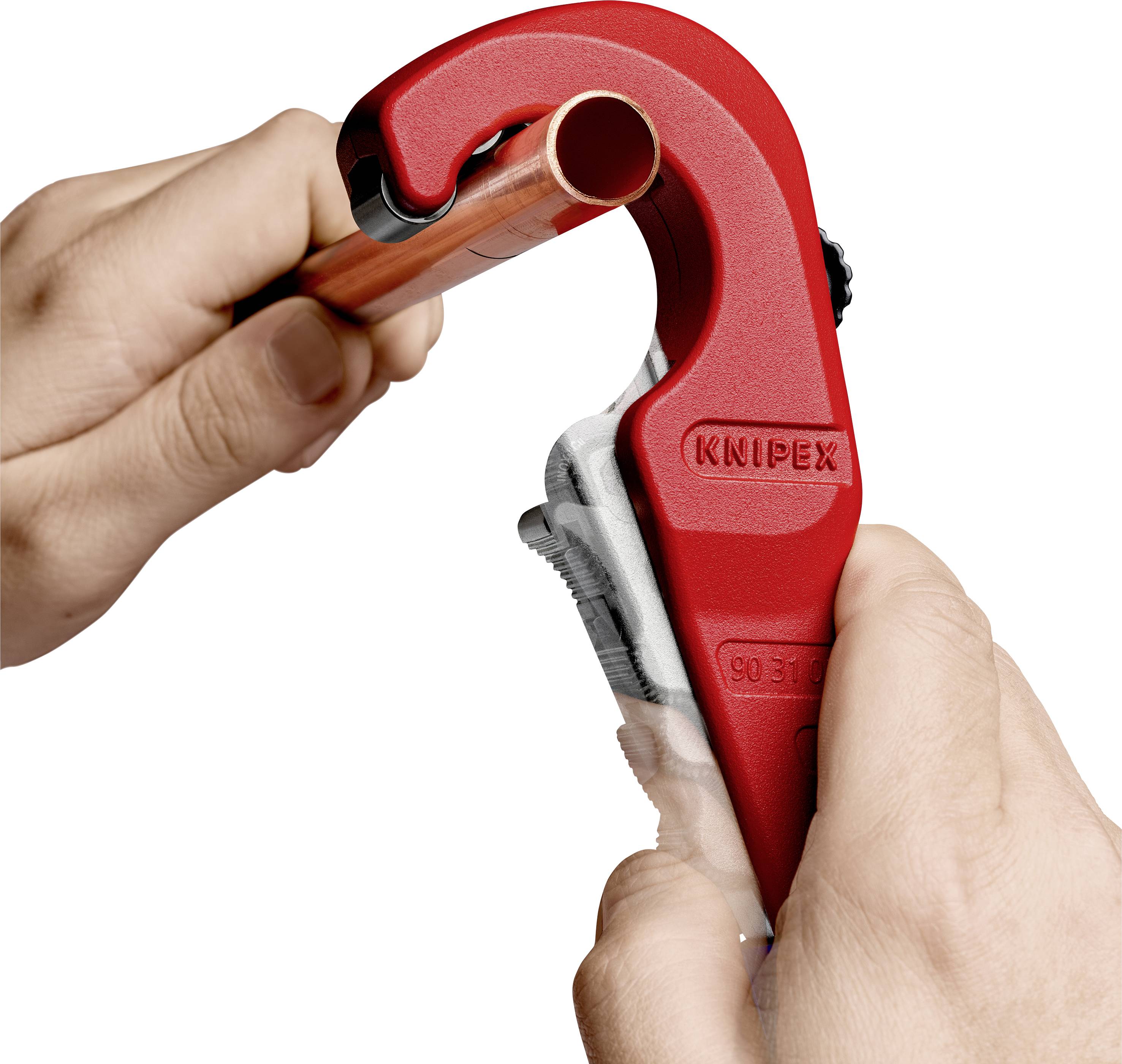 A hand is using a red pipe cutter to cut a copper pipe.