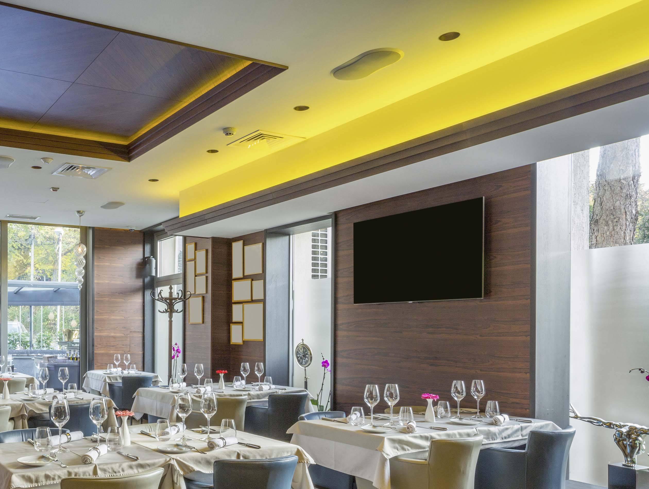 An elegant restaurant with laid tables, white tablecloths and wine glasses. The walls are wood-panelled, and there is warm overhead lighting.