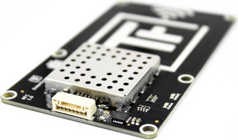 Electronic circuit board with a metallic, perforated module in the centre, connection socket on the side; most likely a radio sensor.