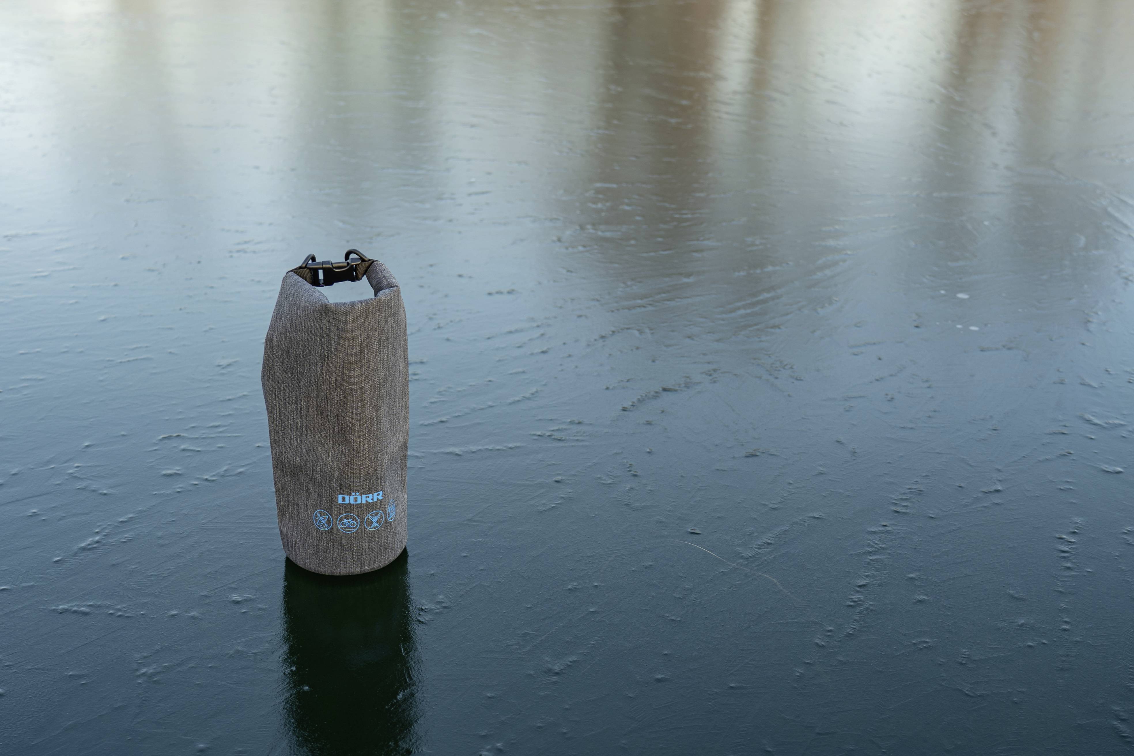 A brown waterproof bag sits on a frozen water surface.