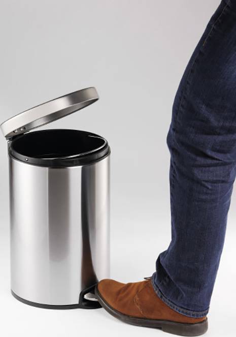 A person steps on the pedal of an open, silver rubbish bin to lift the lid.